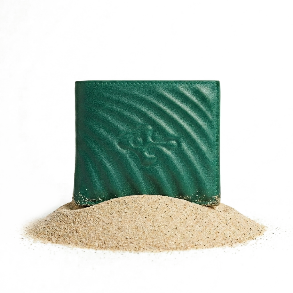 RAVISAUCE Shell bifold wallet — emerald, top grain leather, resting on sand